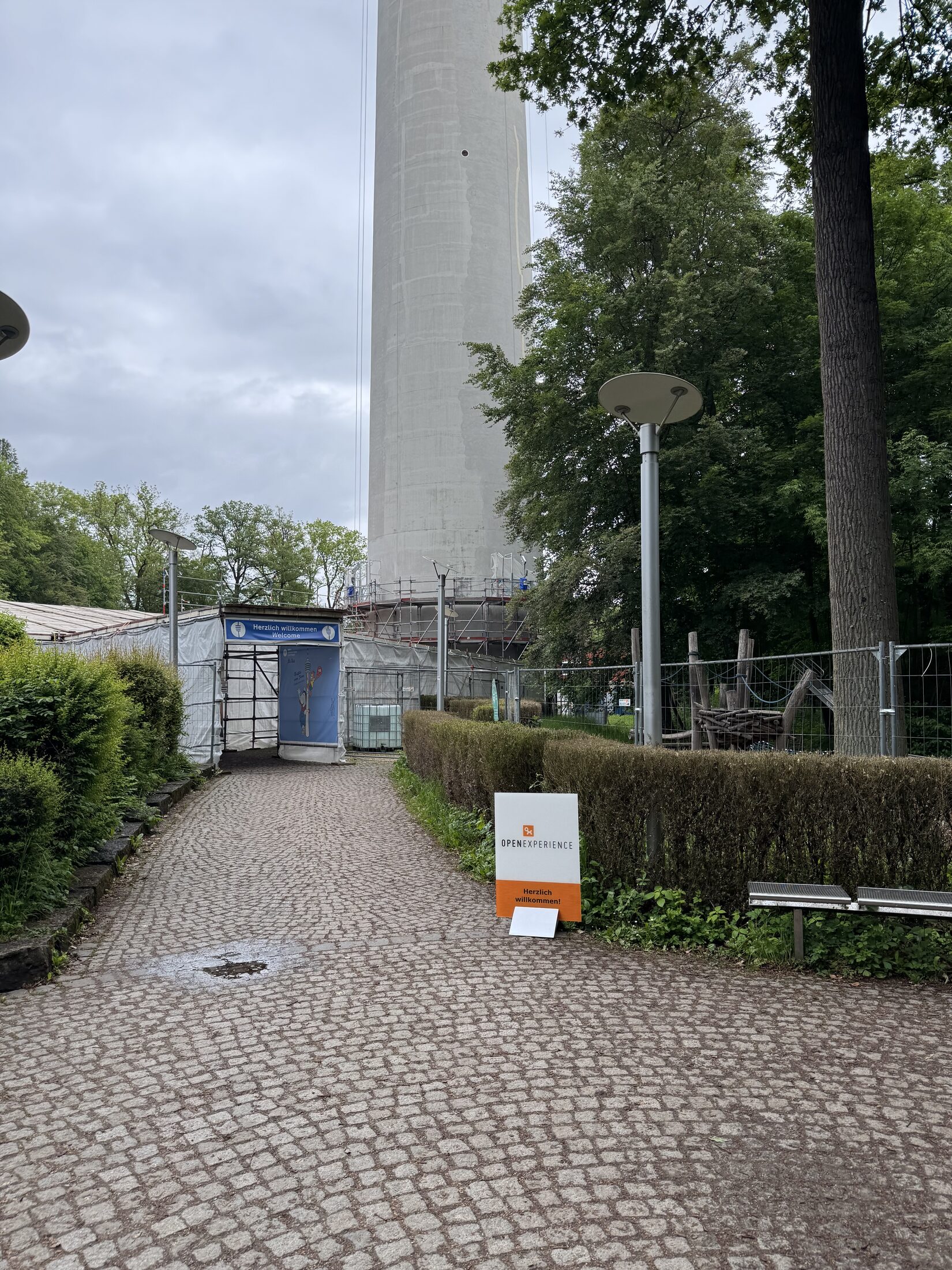 Anreise zur Eventebene — Kopfsteinpflaster-Weg unter dem Fernsehturm mit OX-Willkommensschild